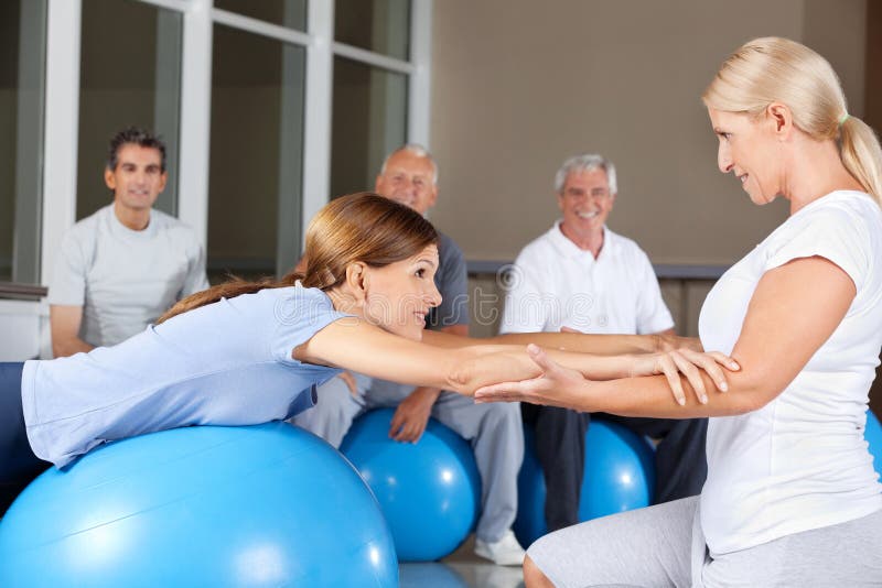 Fitness trainer helping woman stock photos