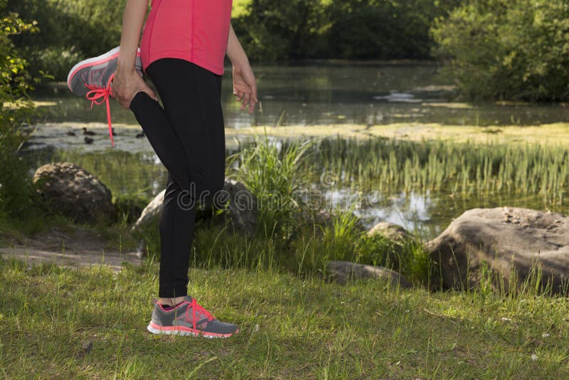 Fitness vrouw die haar benen uitrekken in openlucht tijdens sporten stock fotografie Fitness vrouw die haar benen uitrekken in openlucht tijdens sporten stock fotografie