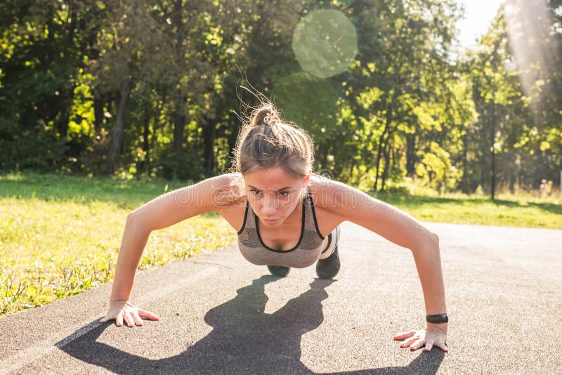 Fitness woman doing push-ups during outdoor cross training workout. Beautiful young and fit fitness sport model training