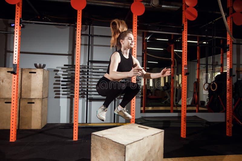 Fit young woman box jumping at a cross fit gym