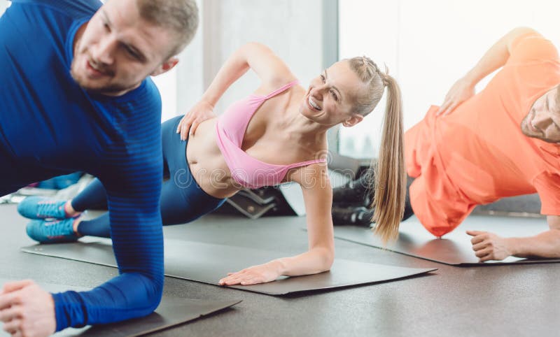 Fitness woman and men in the health club doing a side plank