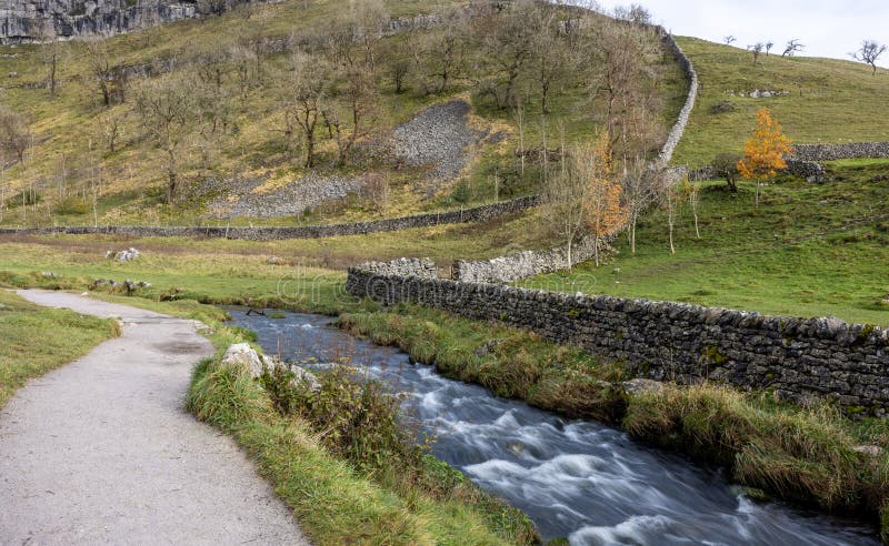 A peaceful stream meandering through a valley by a rocky mountain. A peaceful stream meandering through a valley by a rocky mountain