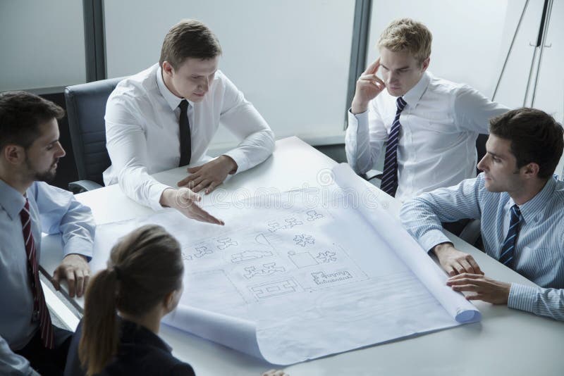 Five architects discussing and planning over a blueprint in the office stock photography Five architects discussing and planning over a blueprint in the office stock photography