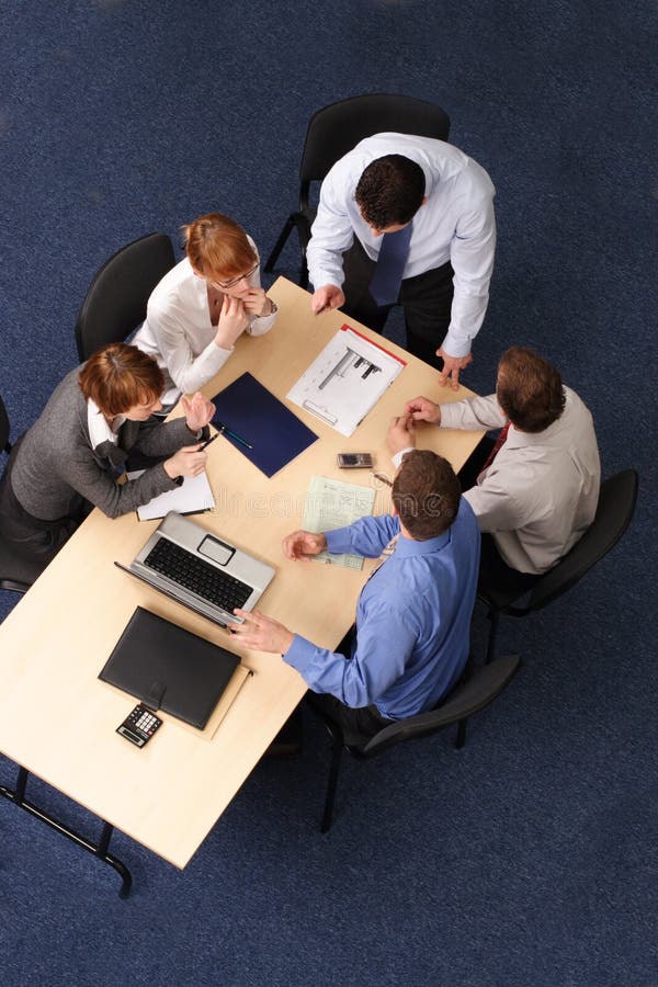 Businesspeople gathered around a table for a meeting, brainstorming. Aerial shot taken from directly above the table. Businesspeople gathered around a table for a meeting, brainstorming. Aerial shot taken from directly above the table.