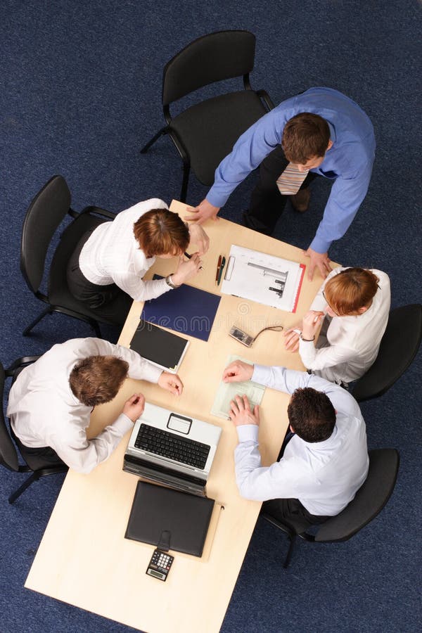 Businesspeople gathered around a table for a meeting, brainstorming. Aerial shot taken from directly above the table. Businesspeople gathered around a table for a meeting, brainstorming. Aerial shot taken from directly above the table.