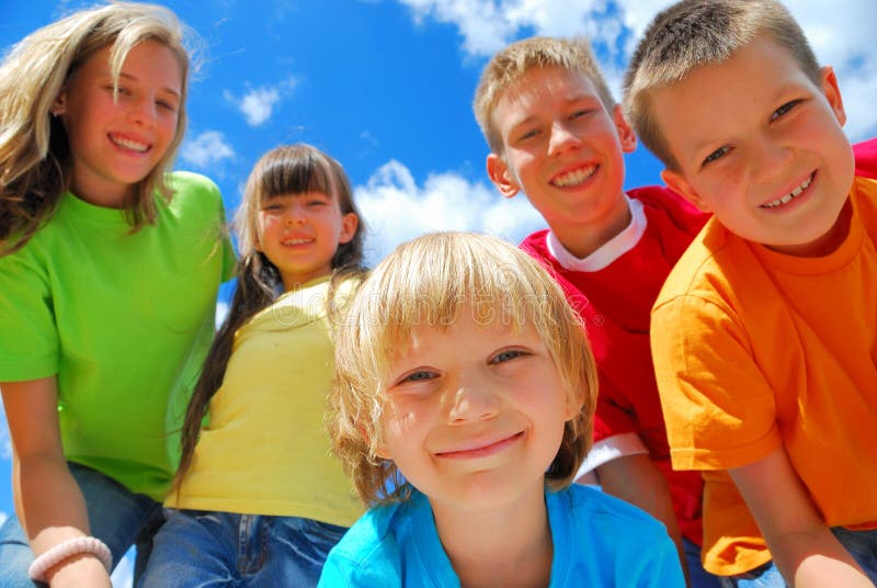 Eine Gruppe von fünf glückliche Kinder mit einem blauen Himmel hinter Ihnen.