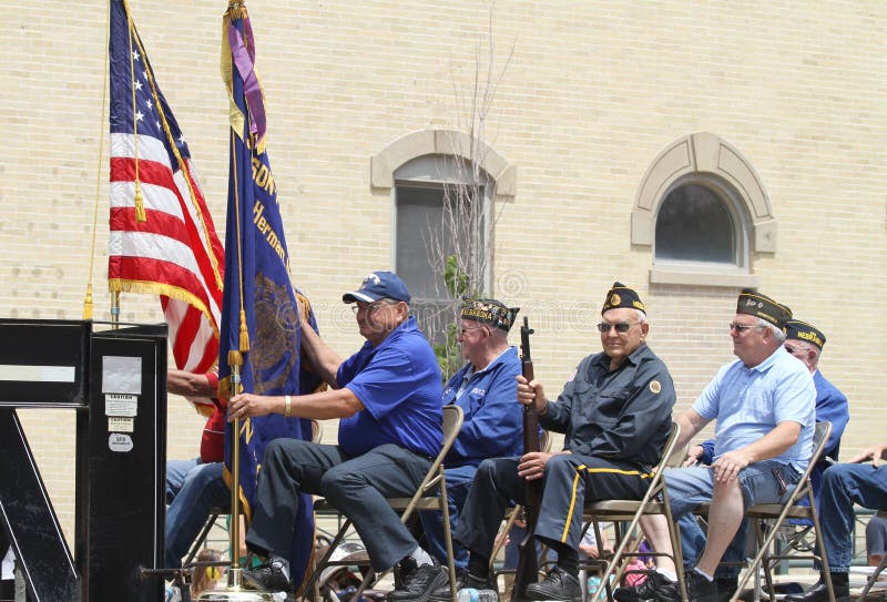 Five older veterans on a float with flags in a parade in the street in summer in small town America. Five older veterans on a float with flags in a parade in the street in summer in small town America