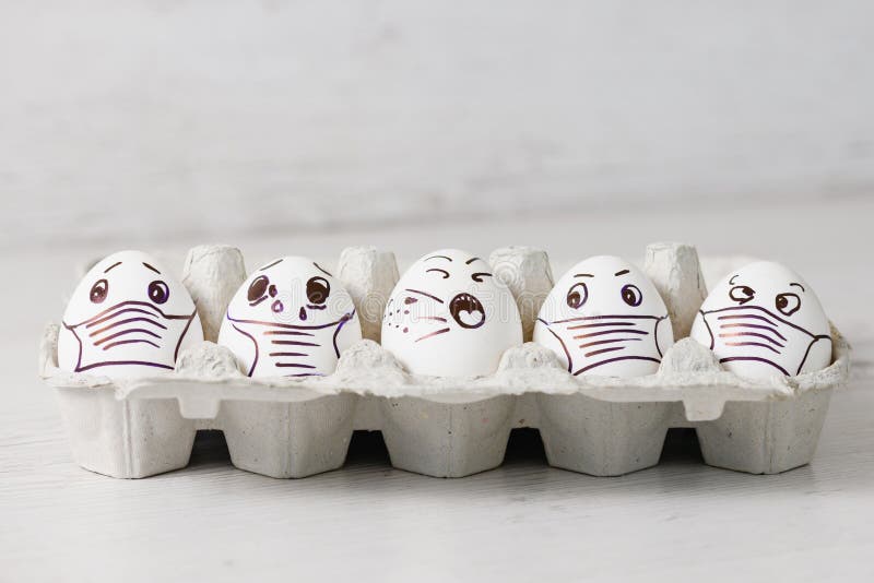 Five unhappy Easter holiday eggs in masks. Tray of white eggs with drawn funny desperate crying faces wearing medical masks at Easter holiday during coronavirus epidemy close up