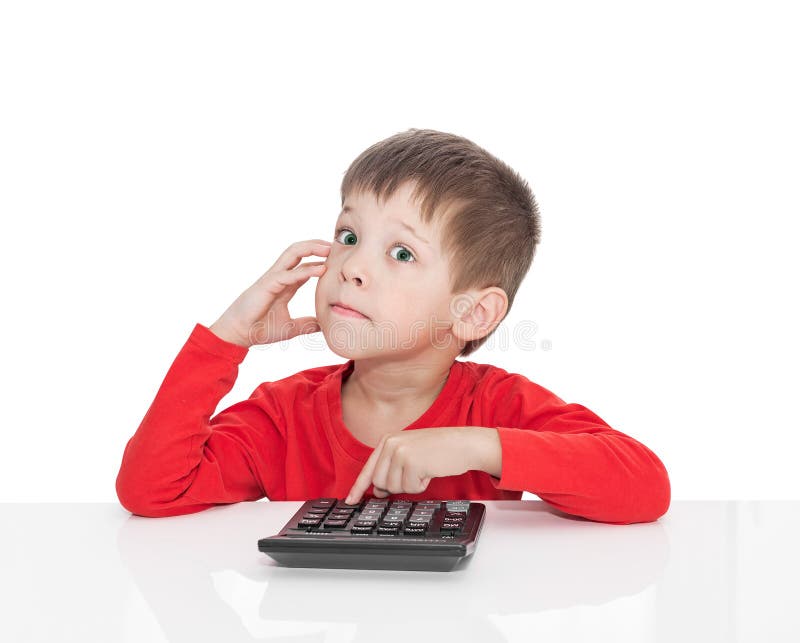 The five-year boy sitting at a white table and presses the button calculator