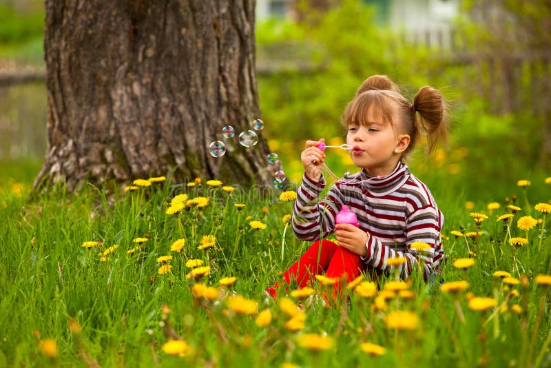 Five-year girl blowing soap bubbles in the park