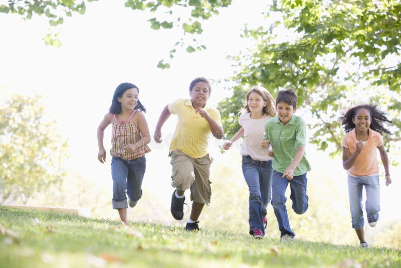 Five young friends running outdoors smiling.
