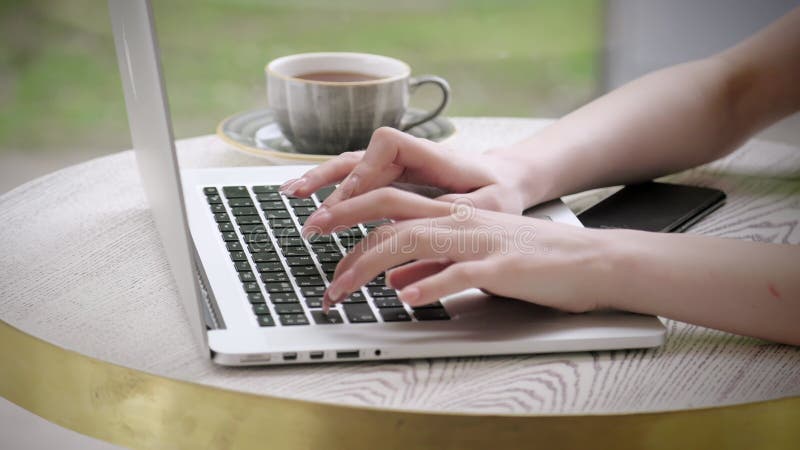 Fixer les objectifs. Mains manucure femelles taper sur le café tasse pour ordinateur portable sur la table. Mains de types clavier banque de vidéos