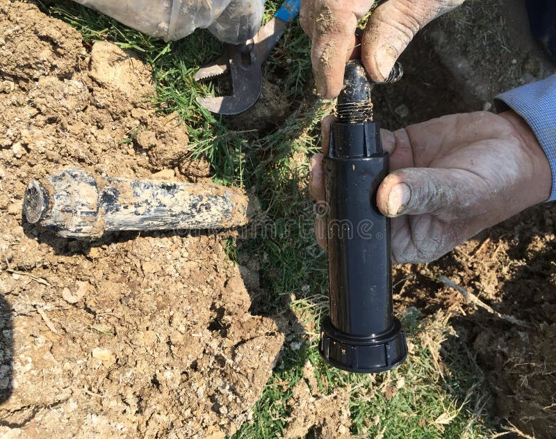 Fixing broken lawn sprinkler stock photo