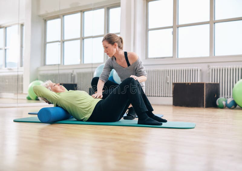 Fizycznego terapeuta pomaga stara kobieta przy gym