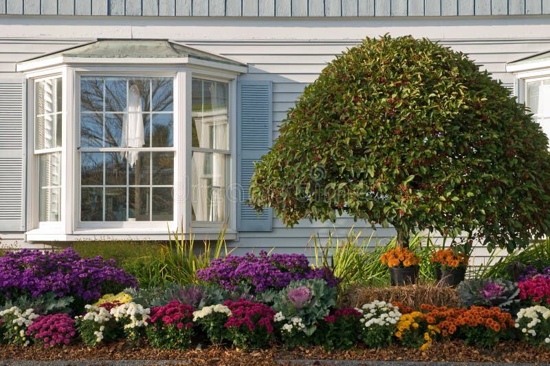 Autumn flower gardening and landscaping beside a house with a large bay window. Autumn flower gardening and landscaping beside a house with a large bay window.