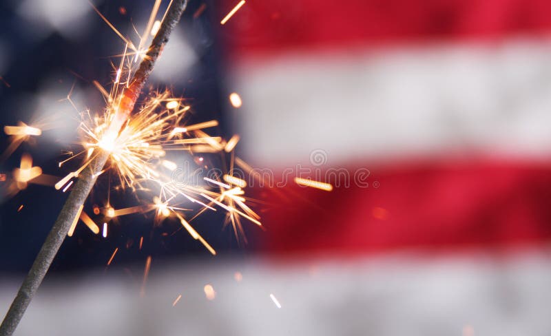 A fourth of july sparkler on a usa flag background. A fourth of july sparkler on a usa flag background.