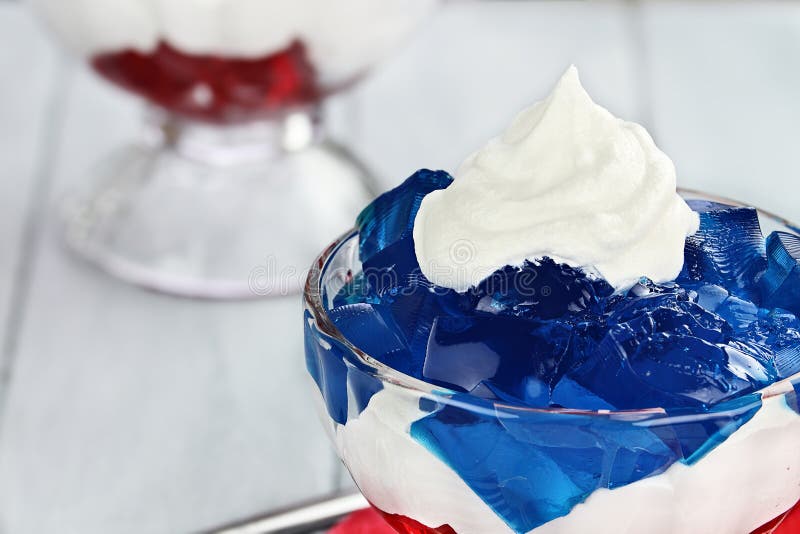 Gelatin layered dessert of cubes of red and blue jello with white fluffy whipped cream for the Fourth of July holiday. Shallow depth of field. Gelatin layered dessert of cubes of red and blue jello with white fluffy whipped cream for the Fourth of July holiday. Shallow depth of field.