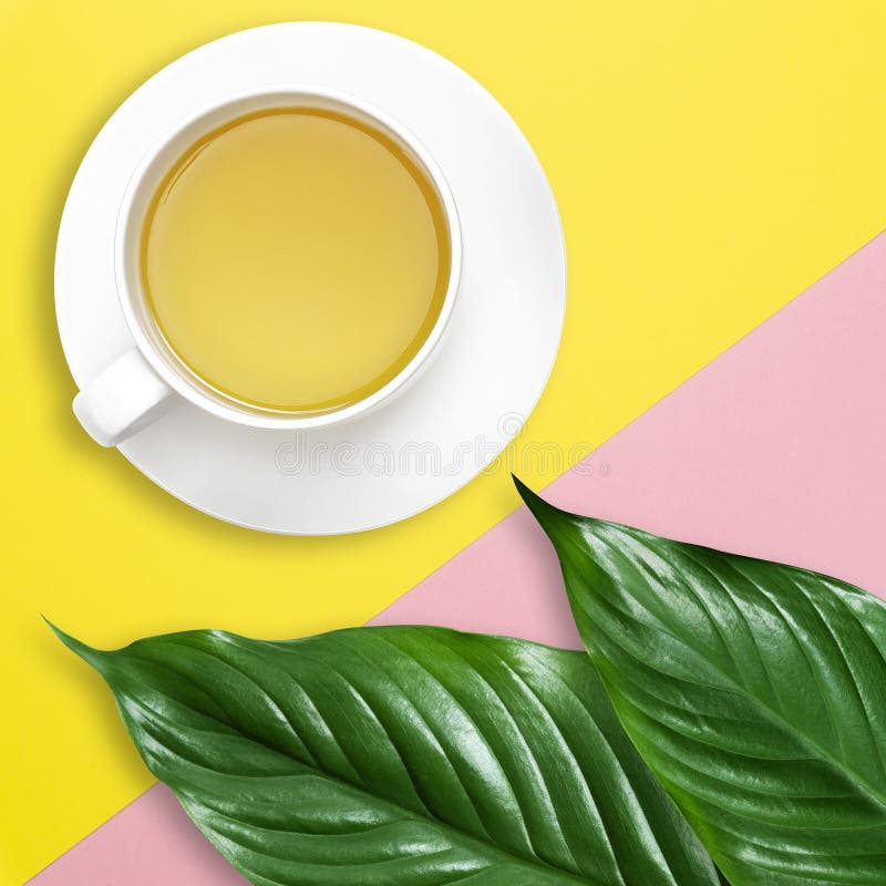 Flache gelegte Schreibtischarbeit des grünen tropischen Blattes und der Teeschale mit Kopienraum, auf blauem rosa Pastellhintergr stockfotografie Flache gelegte Schreibtischarbeit des grünen tropischen Blattes und der Teeschale mit Kopienraum, auf blauem rosa Pastellhintergr stockfotografie