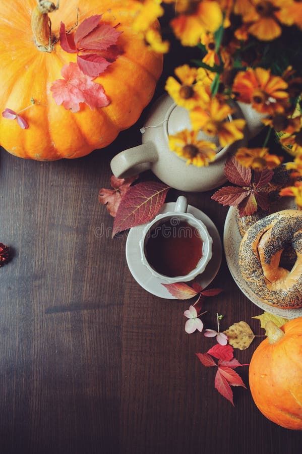 Flache Lage des gemütlichen Herbstfrühstücks auf Tabelle im Landhaus Heißer Tee, Kürbise, Bagel und Blumen stockfoto