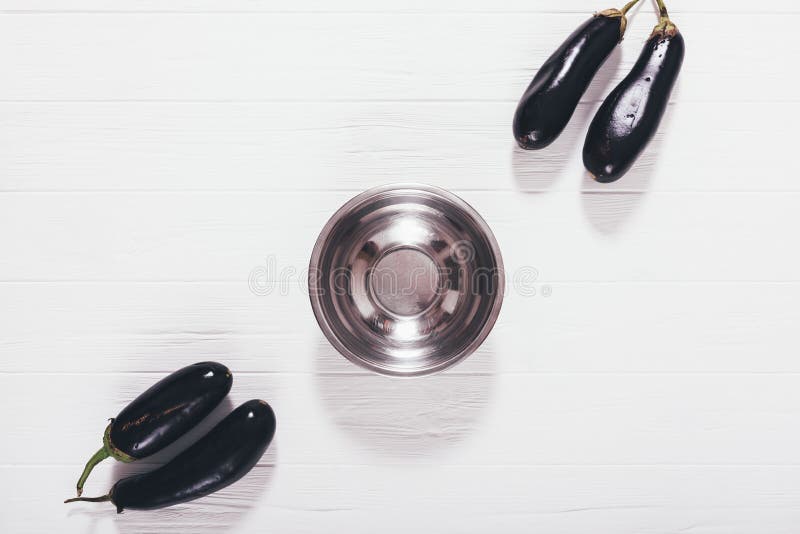 Flache Plangruppe Auberginen gesetzt nahe leerem Edelstahlteller lizenzfreies stockbild