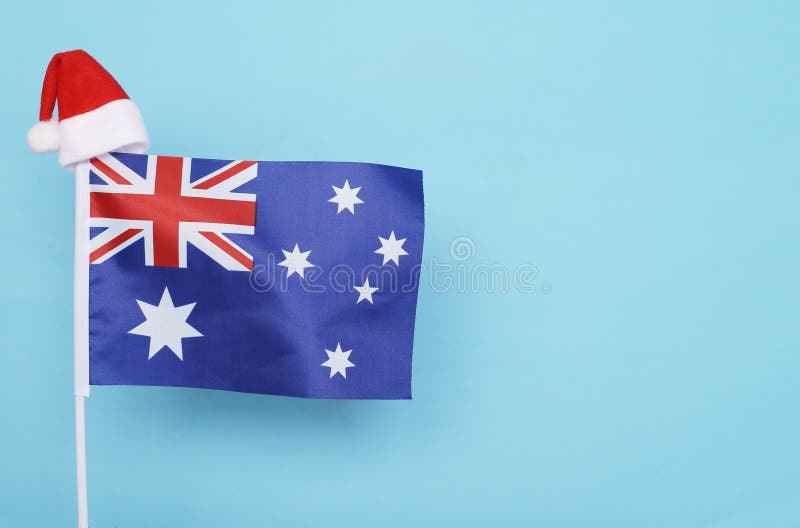 Flag of Australia with little santa claus hat on blue background. New Year winter holiday concept, copy space