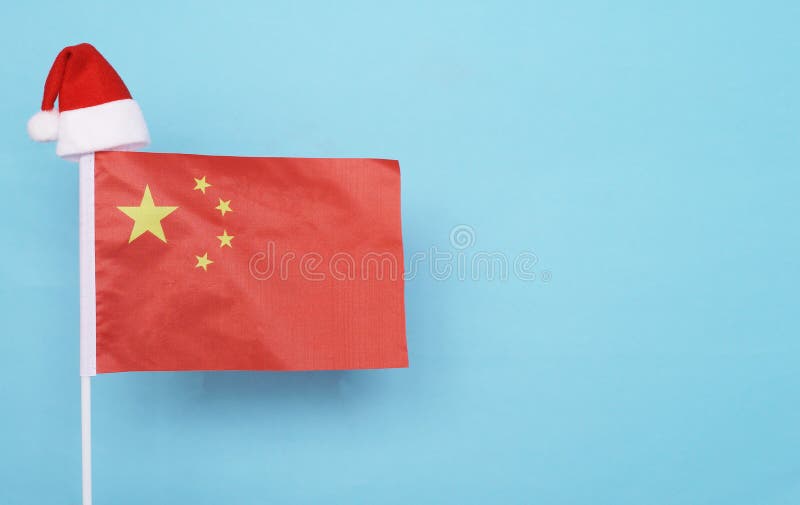 Flag of China with little santa claus hat on blue background. New Year winter holiday concept, copy space