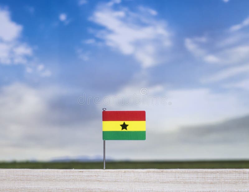 Flag of Ghana with vast meadow and blue sky behind it. stock image