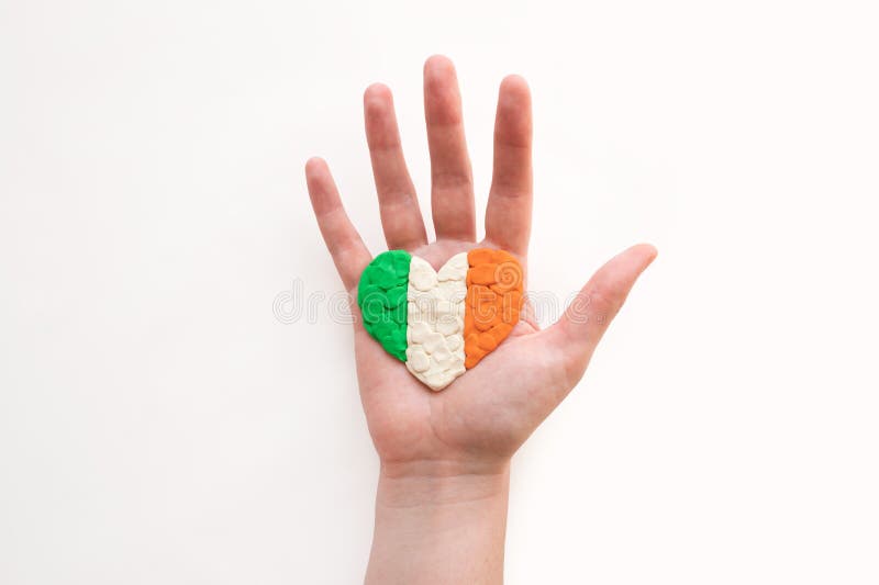 Flag of Ireland. Heart shape of green, white and orange plasticine modeling clay in female palm hand on white background. Irish