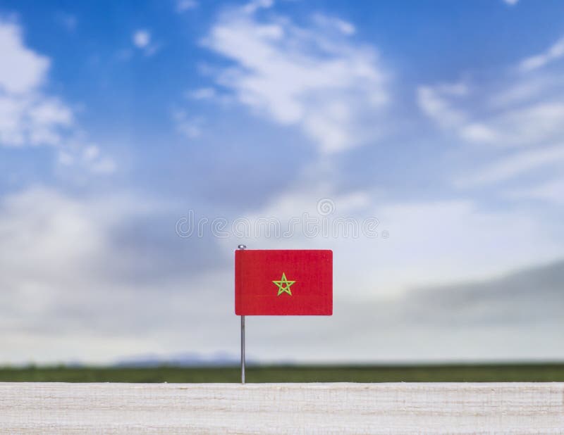 Flag of Morocco with vast meadow and blue sky behind it. royalty free stock photos