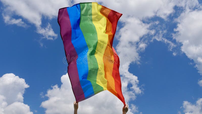 LGBT flag in hands on the background of the sky royalty free stock image