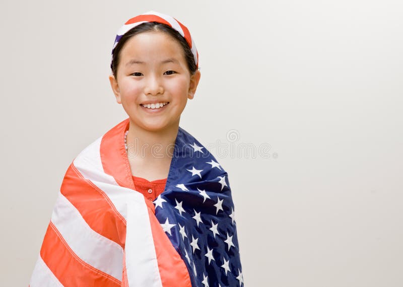 Patriotic girl with American flag around her shoulders and American flag headband. Patriotic girl with American flag around her shoulders and American flag headband