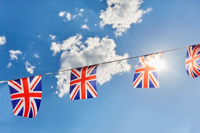 Flaggenflaggen Briten Union Jack gegen blauen Himmel mit Sonne lizenzfreie stockfotografie Flaggenflaggen Briten Union Jack gegen blauen Himmel mit Sonne lizenzfreie stockfotografie