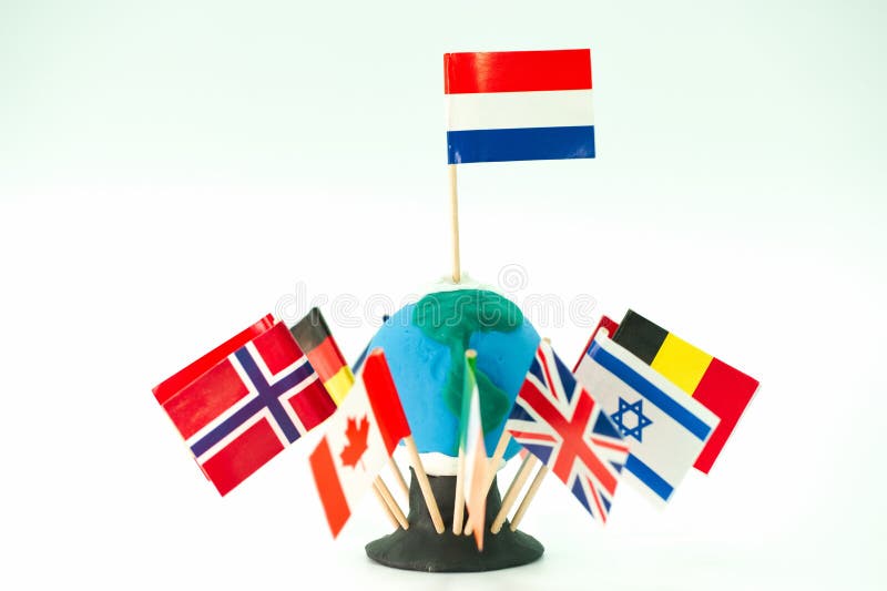 Flags from different countries arranged around a clay model of Earth with toothpicks in a classroom setting stock photography