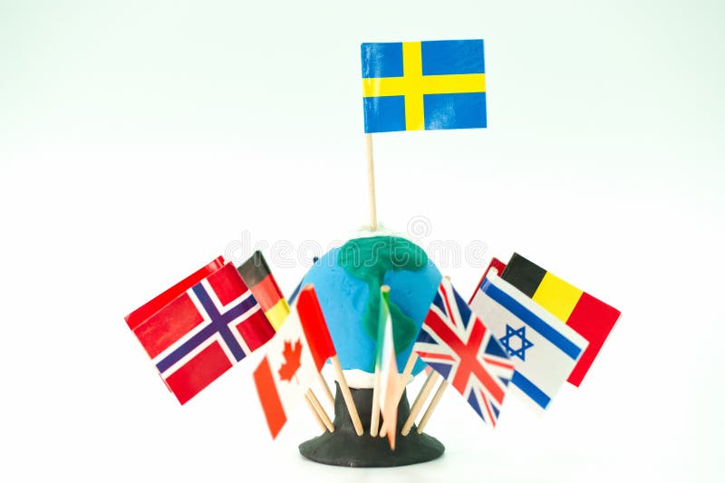 Flags representing different countries displayed on a small globe made of clay with toothpicks in a well lit setting royalty free stock photography