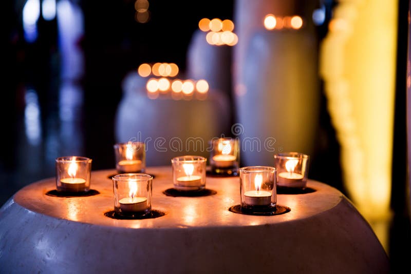 Flame of Many Candles Burning on Blurred Lights Background. Stock Photo