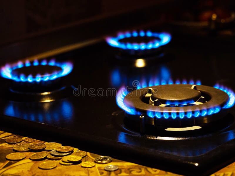 Blue Flames on Gas Stove Burner with Coins, Closeup Stock Photo Image