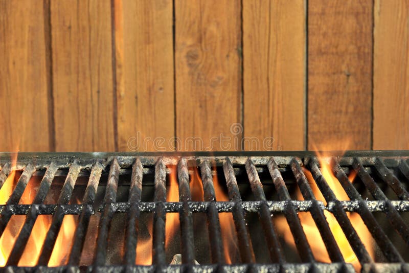 Flaming BBQ Charcoal Cast Iron Grill And Wood Background