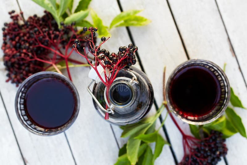 Bottle of elderberry syrup and glasses on a wooden table, top view. Bottle of elderberry syrup and glasses on a wooden table, top view