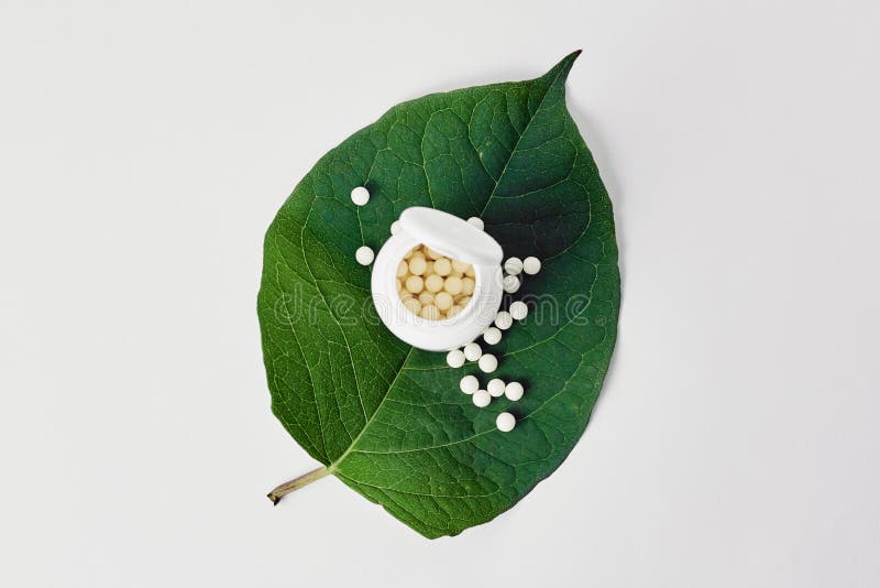 Flasche mit homöopathischen Pillen auf grüngrünem Pflanzenblatt Homöopathie, Neuropathie und alternative Kräutermedizin lizenzfreie stockbilder Flasche mit homöopathischen Pillen auf grüngrünem Pflanzenblatt Homöopathie, Neuropathie und alternative Kräutermedizin lizenzfreie stockbilder