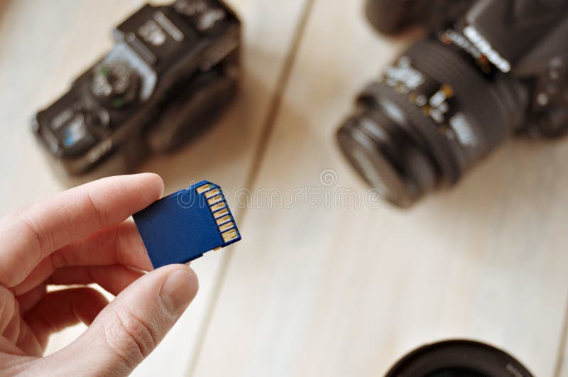 Flash card in hand on camera background, memory card for SLR camera, flash drive, photo storage stock image