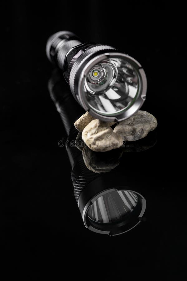 Flashlight LED on stones mirroring on black background. Useful for adventure, military, hunting, outdoor, protection, security, background presentation. Mirroring object stock images, royalty-free photos and pictures