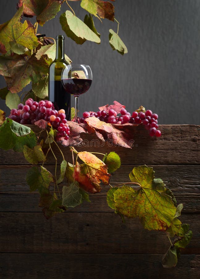 Flask- och exponeringsglasrött vin med druvor på en gammal trätabell royaltyfri bild Flask- och exponeringsglasrött vin med druvor på en gammal trätabell royaltyfri bild