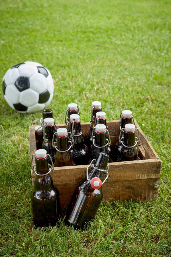 Flaskor av hantverköl eller lager med en fotbollboll royaltyfri fotografi Flaskor av hantverköl eller lager med en fotbollboll royaltyfri fotografi