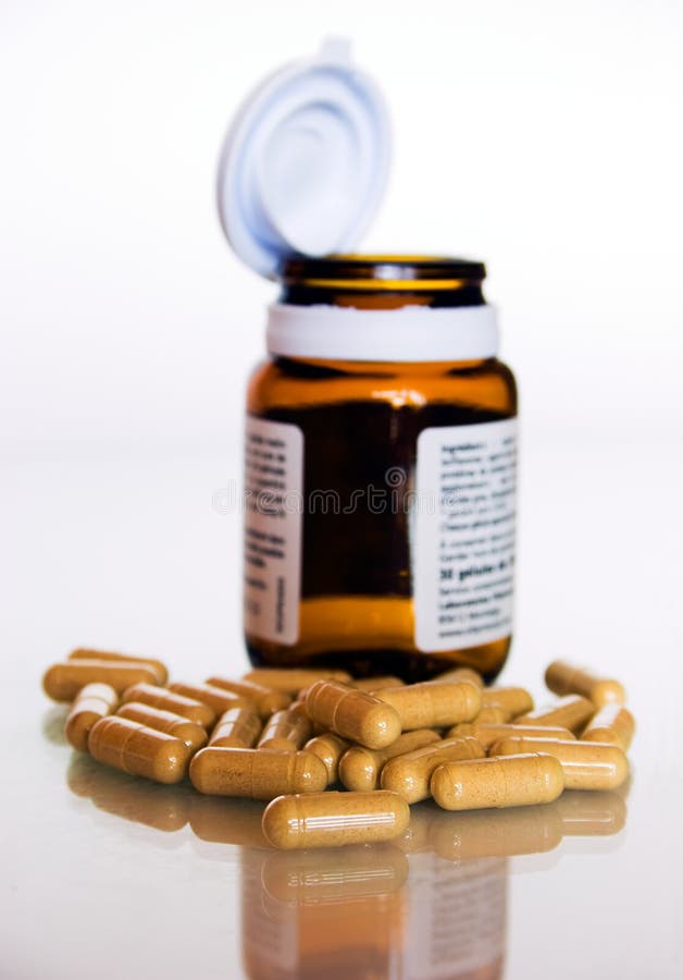 Bunch of pills in foreground and blurred open bottle in background. Bunch of pills in foreground and blurred open bottle in background