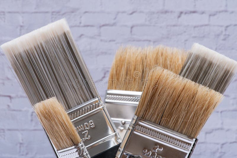 Flat Chip and Flat Cut Utility Paint Brushes on Brick Wall Stock Photo