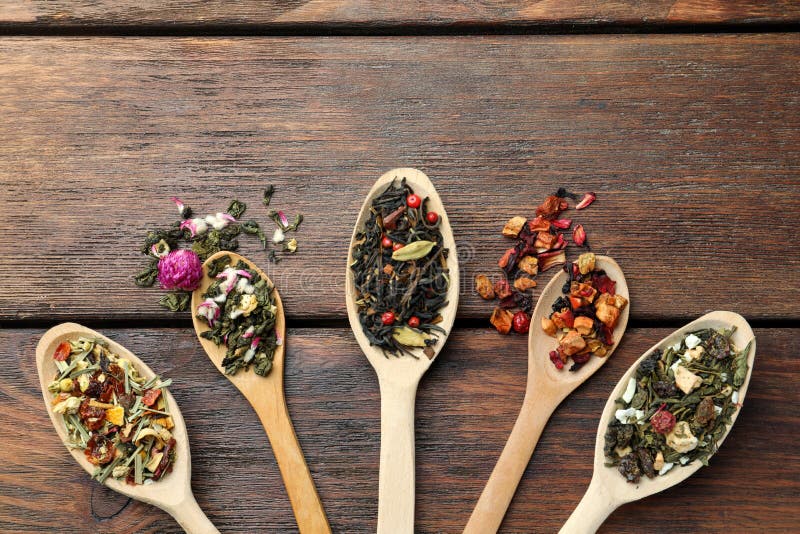Flat composition with spoons of dried herbal tea leaves on wooden table. Space for text stock photo
