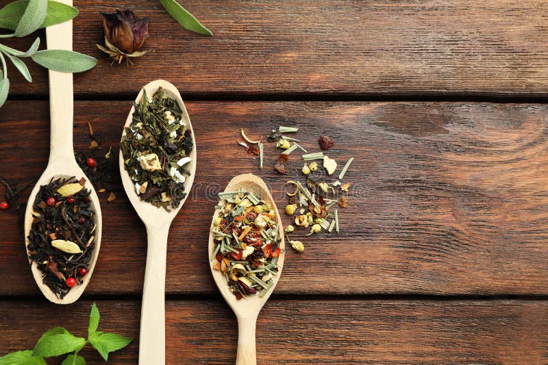 Flat composition with spoons of dried herbal tea leaves on wooden table. Space for text royalty free stock photography