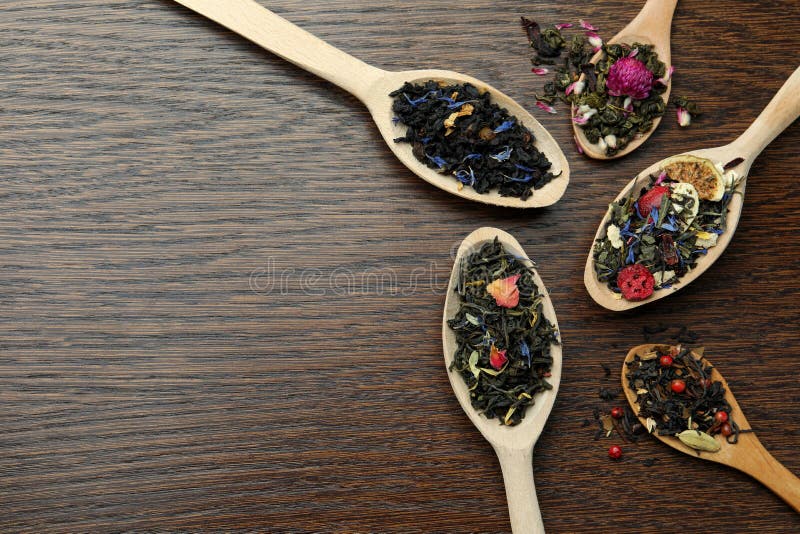 Flat composition with spoons of dried herbal tea leaves on wooden table. Space for text stock photos