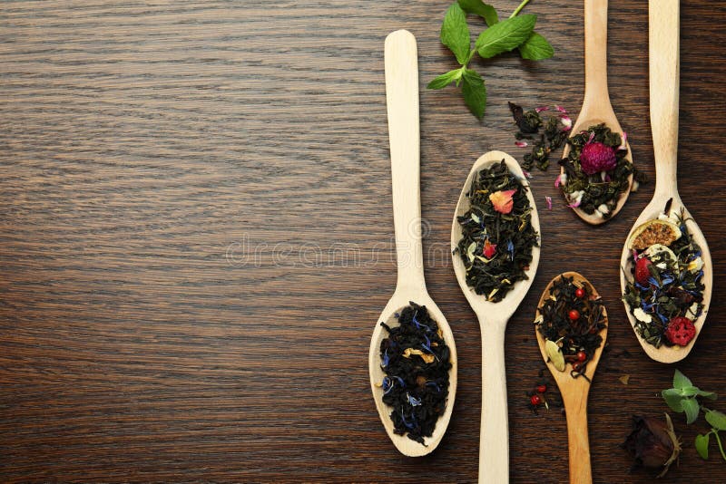 Flat composition with spoons of dried herbal tea leaves on wooden table. Space for text stock image