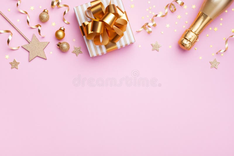 Flat lay border for Christmas or New year banner. Champagne bottle, gift or present box and golden confetti on pink top view stock image Flat lay border for Christmas or New year banner. Champagne bottle, gift or present box and golden confetti on pink top view stock image